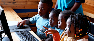 Fotografía de niños y niñas sentods frente a un computador