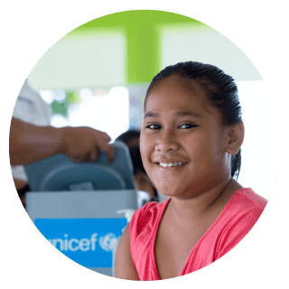 nina feliz con el logo de unicef mirando a la camara