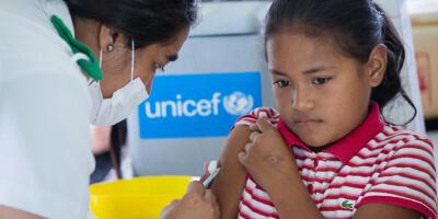 ninca siendo vacunada por funcionaria de UNICEF
