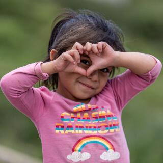 una niña haciendo un corazon con la mano