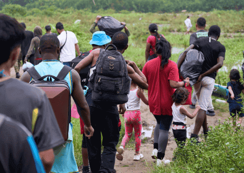 personas caminando con paquetes y niños dejando sus hogares