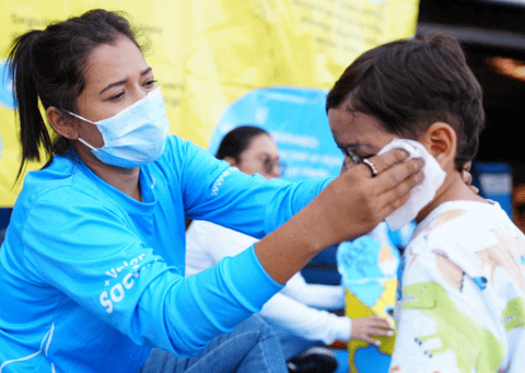Funcionario de UNICEF limpiandole la cara a niño