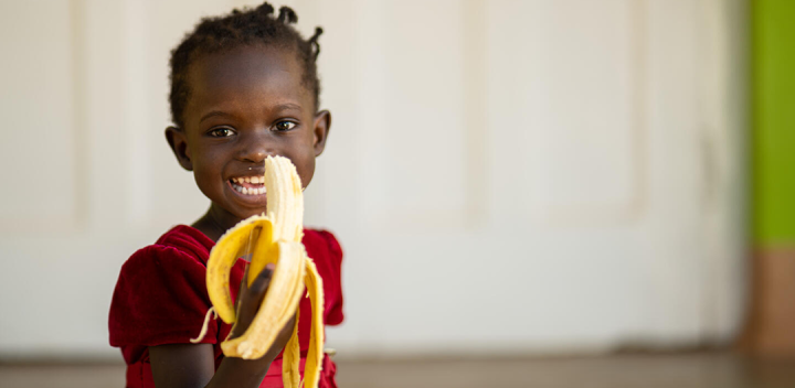 Niña comiendo banano