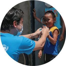 nino jugando con lupa junto a un colaborador de UNICEF Colombia