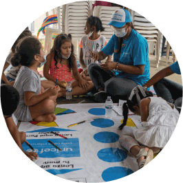 niños coloreando y jugando con colaboradora de UNICEF