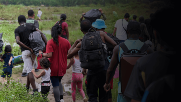 personas caminando con sus pertenencias en una sola fila