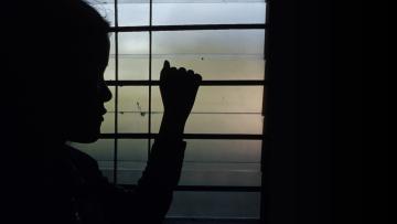 niña mirando por una ventana con temor por la violencia